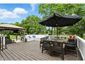 Outdoor dining on a wooden deck with a large umbrella, set against a backdrop of lush greenery at 10113 Gallop Ln, Fishers, IN 46040