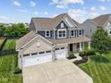 Elevated view of a brick and siding home with a three car garage and manicured lawn at 1306 Avocet Dr, Greenwood, IN 46143