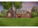 Charming brick home with a well-manicured lawn and mature trees during the twilight at 1411 N Claridge Way, Carmel, IN 46032