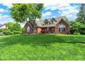 Beautifully landscaped front yard of brick home with mature trees and a long driveway at 1411 N Claridge Way, Carmel, IN 46032