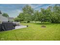 Expansive backyard with mature trees, a fire pit, a concrete patio, and access to a scenic pond at 16095 Tenor Way, Noblesville, IN 46060