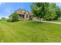 A large home on a green lawn, featuring stone and siding, a three-car garage and a covered porch at 16548 Grand Cypress Dr, Noblesville, IN 46060