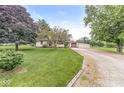 A classic ranch-style home with gravel driveway and a green lawn, shaded by beautiful mature trees at 4010 S Bazil Ave, Indianapolis, IN 46239
