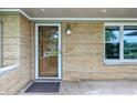 Inviting front entry featuring a storm door, brick facade, exterior lighting, and adjacent window at 5205 Staughton Dr, Indianapolis, IN 46226