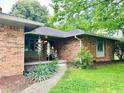 Inviting brick home entrance with covered porch and green lawn at 7721 Hollybrook Ln, Indianapolis, IN 46227