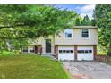 Split-level home featuring a two-car garage, siding, and landscaped front yard at 8920 Caminito Rd, Indianapolis, IN 46234