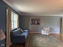 Spacious living room with a blue sofa, hardwood floors, and a large window that brings in tons of natural light at 9011 Camby Rd, Camby, IN 46113