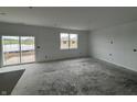 Unfinished living room featuring a sliding glass door leading to the backyard, a window, and white walls at 9137 Steinbeck Ln, Indianapolis, IN 46239
