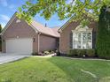 Charming brick home featuring a well-manicured lawn, flowers and a two-car garage at 9302 N Bayland Dr, McCordsville, IN 46055