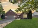 Charming brick home featuring a well-manicured lawn and a two-car garage at sunset at 9302 N Bayland Dr, McCordsville, IN 46055
