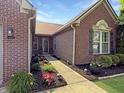 Charming brick home featuring a well-manicured lawn, flowers and walkway to the front door at 9302 N Bayland Dr, McCordsville, IN 46055