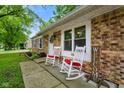 Welcoming front porch with white rocking chairs, brick facade, and verdant landscaping at 99 Old Trail Dr, Bargersville, IN 46106