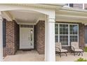 Inviting front porch with seating area, brick accents, and a bright white front door at 10811 Wild Orchard Ln, Indianapolis, IN 46239