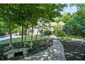 Stone path leads to a stone bench and mulched area, and view of the stone home at 11557 Willow Springs Dr, Zionsville, IN 46077