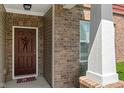 Close-up of a welcoming front door with brick accents, decorative wreath, and a patriotic welcome mat at 13992 Wynngate Ln, Fishers, IN 46038