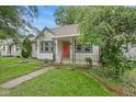 Inviting home showcasing lush landscaping, a charming front porch, and a vibrant red front door at 1739 Caldwell Pl, Columbus, IN 47201