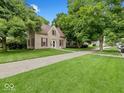 Inviting two-story home with charming red shutters surrounded by a lush green lawn and mature trees at 228 W Washington St, Shelbyville, IN 46176