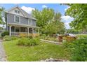 Two-story home with front porch, landscaped yard featuring colorful flowers, and a stone pathway leading to the entrance at 23 S Downey Ave, Indianapolis, IN 46219