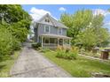 Two-story home with a front porch, a driveway leading to a detached garage, and landscaped yard at 23 S Downey Ave, Indianapolis, IN 46219