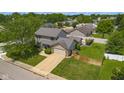 Aerial view of a home with a well-manicured lawn, mature trees, an attached garage, and a long driveway at 2872 N Prairie Stream Way, Columbus, IN 47203