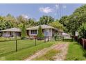 View of the charming single-story home with a black chain-link fence and mature trees at 4218 E 18Th St, Indianapolis, IN 46218