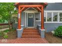 Close up of the home's entrance featuring brick steps, charming pillars, and a stylish front door at 4356 N College Ave, Indianapolis, IN 46205