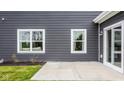 Home featuring gray horizontal siding with two vinyl windows, a white vinyl patio door, and concrete patio at 5002 Jasper Ridge Blvd, Indianapolis, IN 46235