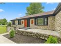 Charming stone home featuring a decorative wood door, landscaped yard, and beautiful exterior lighting at 5550 W Mooresville Rd Byp, Indianapolis, IN 46221