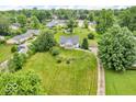 Aerial view showcasing a home with a large front lawn, mature trees, and a long gravel driveway at 1130 E 105Th St, Carmel, IN 46280