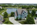 A blue home from above, with a lake and surrounding homes in a developed community at 13895 Cloverfield Cir, Fishers, IN 46038