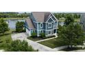 Aerial view of blue home with an attached garage, lake view, mature trees, and a well-manicured lawn at 13895 Cloverfield Cir, Fishers, IN 46038