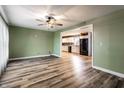 Open-concept living room with wood-look flooring, ceiling fan, and seamless flow into an eat-in kitchen at 4191 N Graham Rd, Whiteland, IN 46184