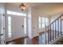 Bright foyer with hardwood floors, a staircase with white railings, and a view into an adjacent room at 6471 W Clearview Dr, McCordsville, IN 46055