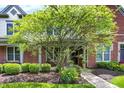 Inviting brick home with a well-maintained front yard, mature tree, and colorful flowerbeds at 6691 Beekman Pl, Zionsville, IN 46077