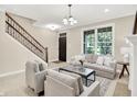 Bright living room featuring neutral decor, a staircase, and a large window offering natural light at 6691 Beekman Pl, Zionsville, IN 46077