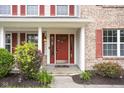 Inviting front entrance with a red door, sidelights, and lush landscaping at 6955 Long Run Dr, Indianapolis, IN 46268