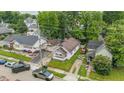 An aerial view shows the house nestled among lush trees, surrounded by neighboring homes in a residential area at 1011 W 7Th St, Anderson, IN 46016