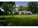 Well-maintained brick home with lush green lawn and mature trees under a colorful sky at 1015 Fox Hill Dr, Indianapolis, IN 46228
