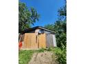 Old shed, surrounded by trees, shows signs of disrepair with patched siding and boarded up walls at 1031 Blaine Ave, Indianapolis, IN 46221