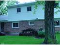 Back exterior featuring brick and siding, with a patio area and mature tree at 1808 Orchid Ct, Indianapolis, IN 46219
