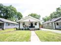 Inviting white house with a covered front porch, green lawn, and lovely curb appeal at 4927 Caroline Ave, Indianapolis, IN 46205