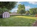 Spacious backyard with a shed, mature trees, green lawn, and a wooden fence, perfect for outdoor activities at 5269 Deer Creek Dr, Indianapolis, IN 46254