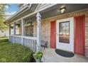 Inviting front porch with brick columns, hanging plants, and a charming front door with red accents at 5269 Deer Creek Dr, Indianapolis, IN 46254