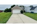 Attached garage with a white door, long driveway, and well-manicured landscaping at 5938 Tybalt Ln, Indianapolis, IN 46254