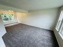 Spacious living room with plush gray carpeting, a window with a view, and a decorative chandelier at 5938 Tybalt Ln, Indianapolis, IN 46254