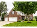 Inviting front of the brick home with attached garage, manicured lawn, and patriotic flag at 6771 Woodcliff Cir, Zionsville, IN 46077