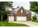 Beautiful exterior featuring a brick facade, attached two-car garage, and lush lawn at 6771 Woodcliff Cir, Zionsville, IN 46077