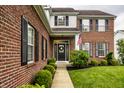 Charming brick home featuring manicured landscaping and wreath on the front door at 6771 Woodcliff Cir, Zionsville, IN 46077