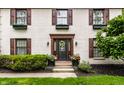 Welcoming front entrance featuring a decorative wreath, stylish sconces, and flower-filled planters at 7743 Camelback Dr, Indianapolis, IN 46250