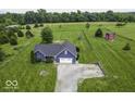 An aerial view shows a blue home with a large lawn, long driveway, and a detached red barn at 911 Centennial Rd, Martinsville, IN 46151